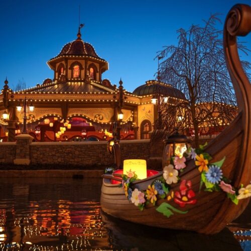 Rapunzel Tangled Spin Buitenkant van de attractie Rapunzel Tangled Spin met een bootje ervoor gedecoreerd met verschillende kleuren bloemen en een goude lampion