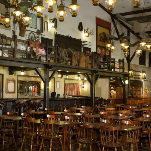 7 Restaurant met bar, houten tafels en stoelen en veel zadels van paarden