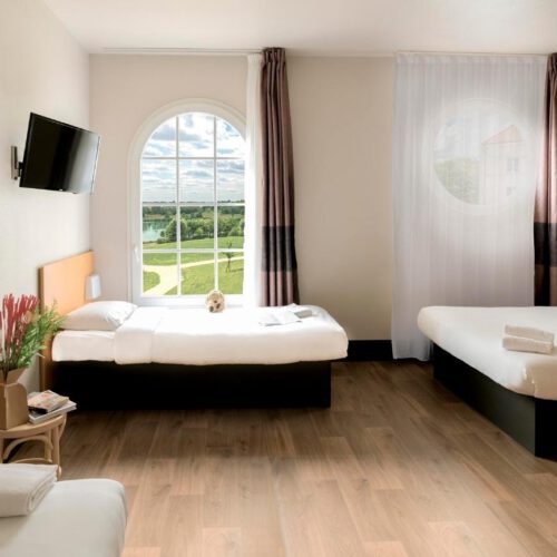 Familiekamer Twee tweepersoonsbeden met een honden knuffel en uitzicht op het water