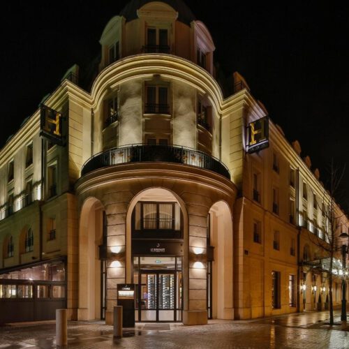 Hotel L'Elysee in avond Verlicht geel gebouw met zwarte kozijnen