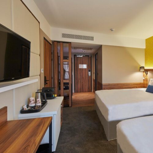 Standaardkamer Tweepersoonsbedden en gele muur met houten accenten