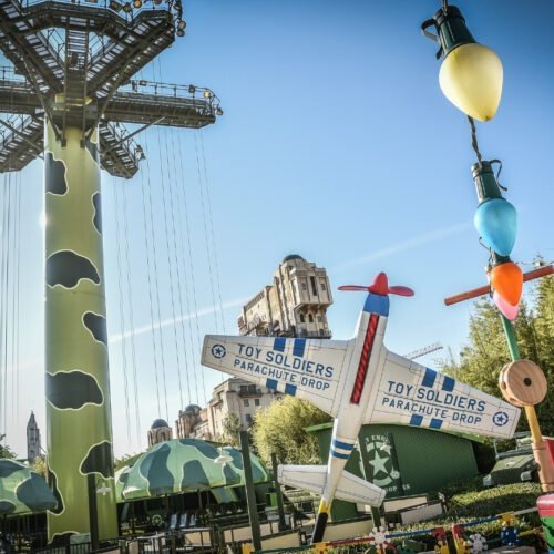 Toy Story - Worlds of Pixar Groene parachutes met daarvoor een groot speelgoed vliegtuig en een kleurrijke slinger van lampjes