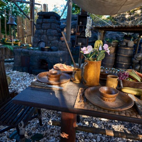 Interieur La Cabane des Robinson Tafel met vaas met bloemen en servies en stoel
