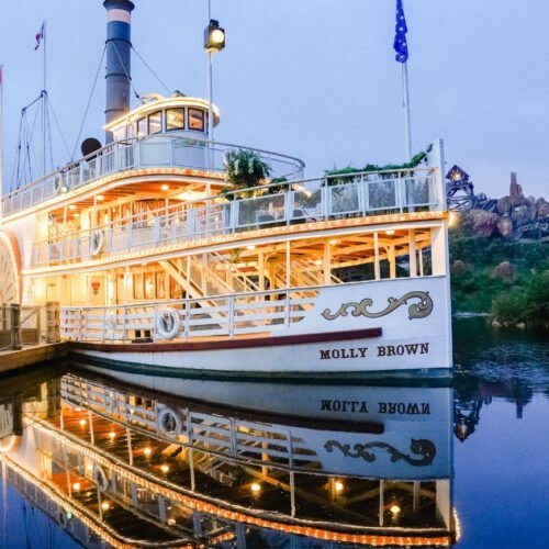 Schip de Molly Brown Het betoverend verlichte schip Molly Brown weerspiegelt in het water van Frontierland tijdens de avondschemering.