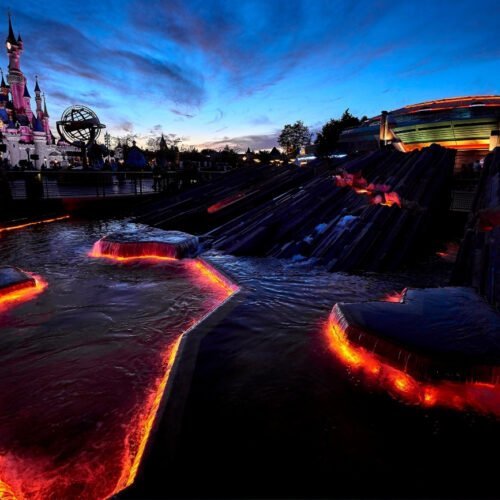 Discoveryland Landschap van rotsen met rode verlichting bij de entree naar Discoveryland. In de schemering kijk je uit over het Kasteel van Doornroosje.