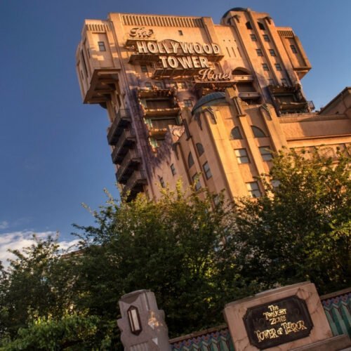 Hollywood Tower of Terror Hollywood Tower of Terror gebouw in Production Courtyard, omlijst door groene struiken, verlicht door zonlicht
