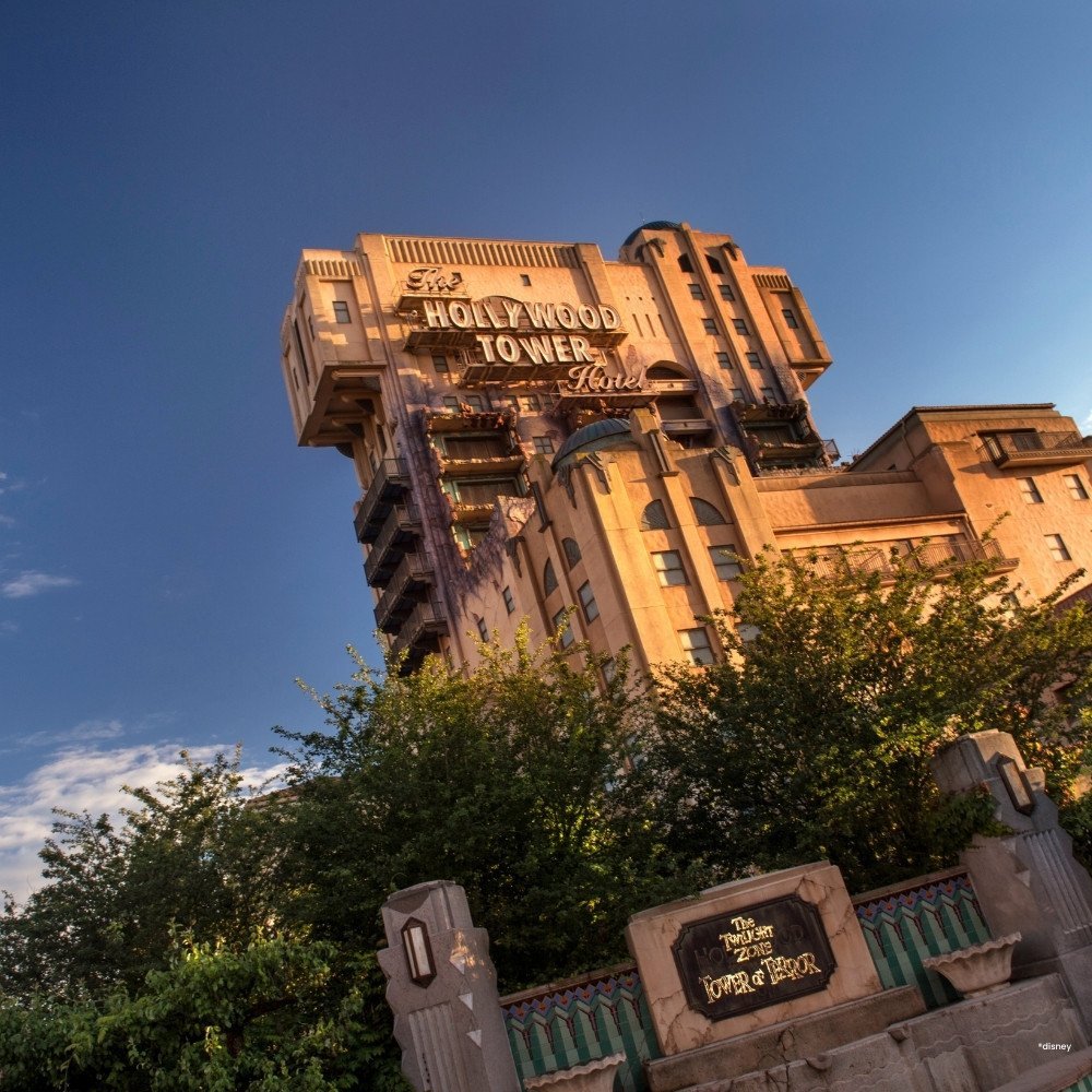 Imposant hoog gebouw van de attractie The Twilight Zone Tower of Terror met groene bomen ervoor
