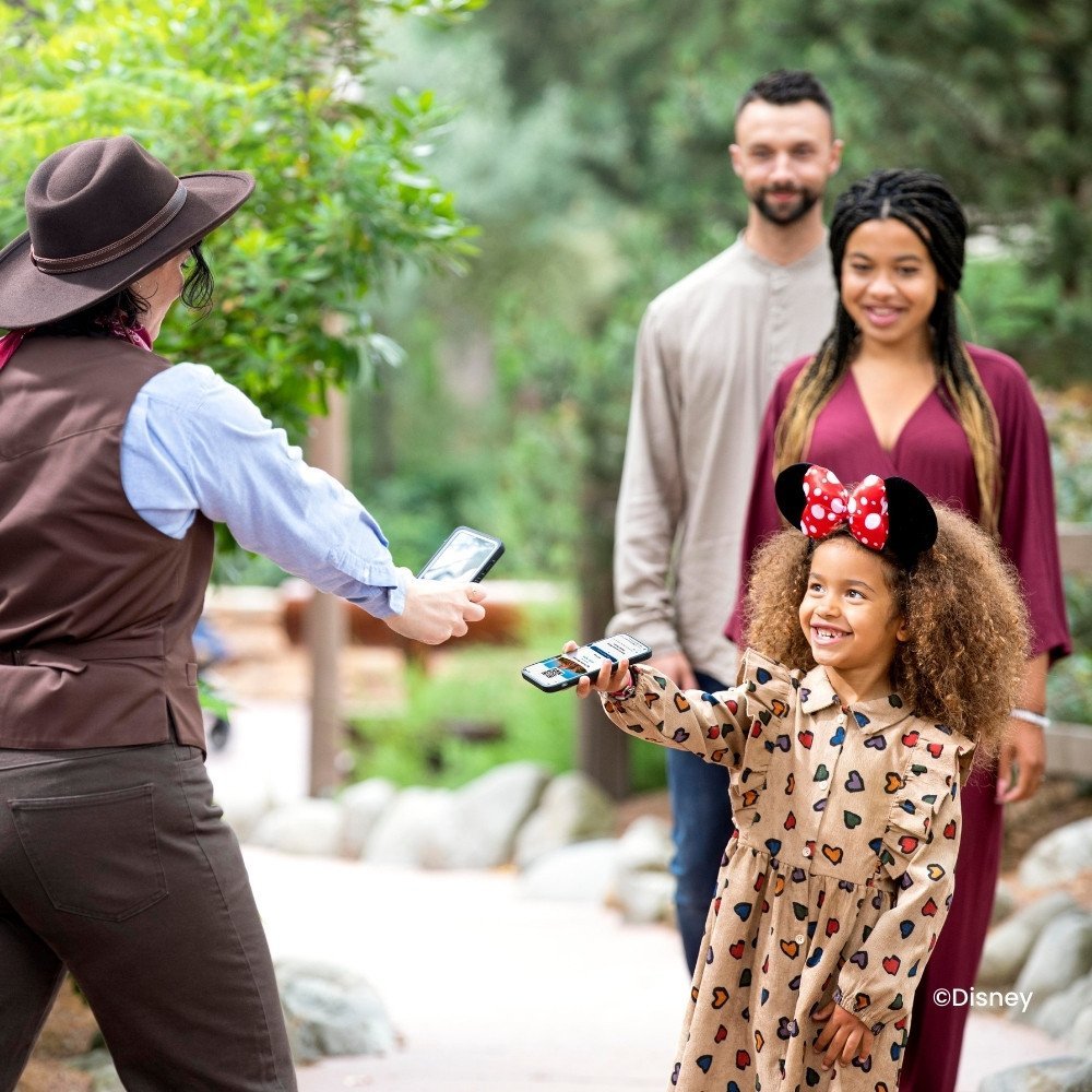 Klein meisje met Minnie Mouse oren die kaartje laat scannen via Disneyland Paris App