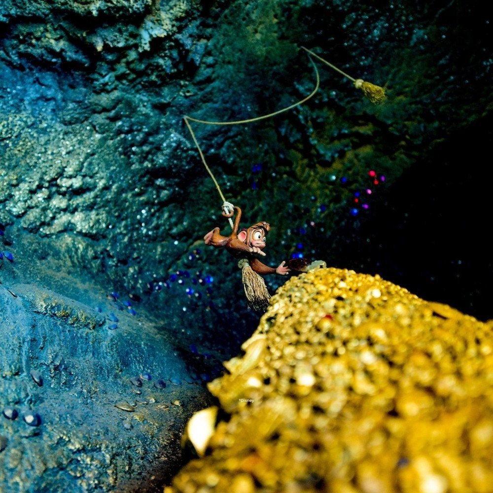 Klein aapje aan een touw in een grot boven een berg goud in de attractie Le Pays des Contes de Fées