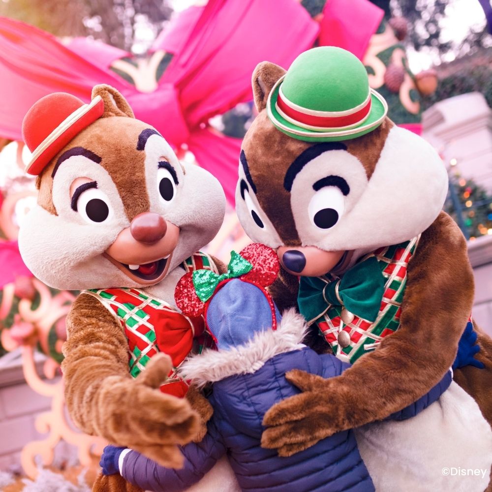 Knabbel en Babbel in hun kerstoutfit geven een knuffel aan een kind tijdens een ontmoeting.