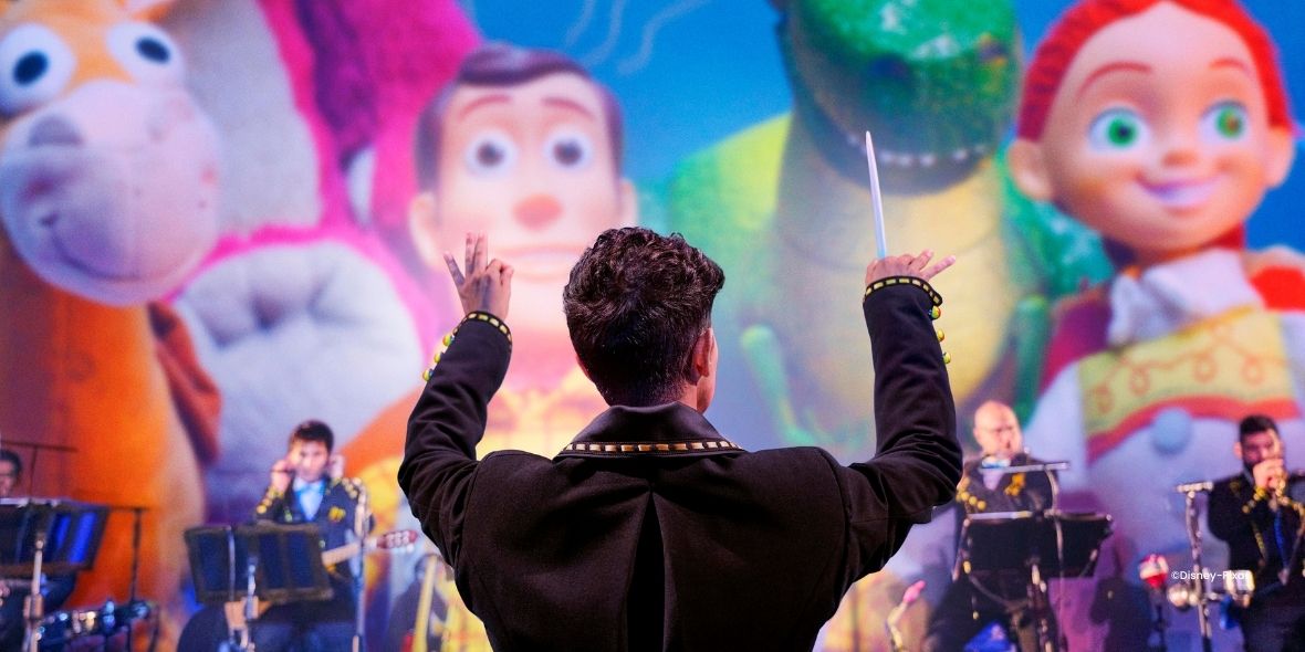 Orkest met dirigent voor een scherm met Disney Pixar Figuren