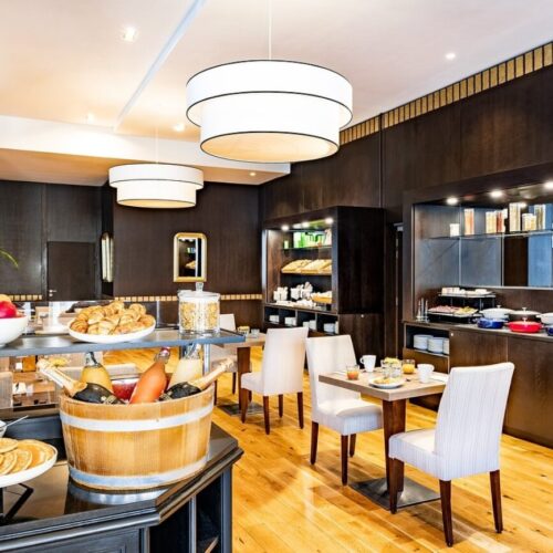 Ontbijtbuffet Ontbijtzaal met uitgebreid buffet, witte stoelen en vierkante tafels