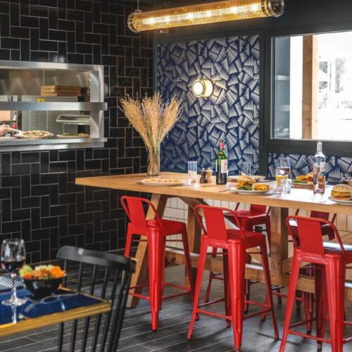 Restaurant Hoge bartafel met rode barkrukken met doorkijk naar de keuken