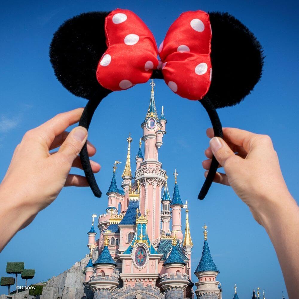 Iemand houdt minnie oortjes vast voor het Kasteel van Doornroosje